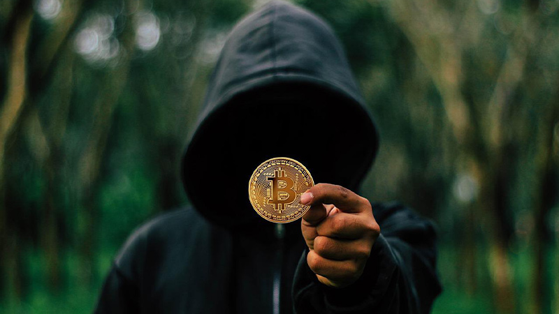 an anonymous person holding a fake bitcoin
